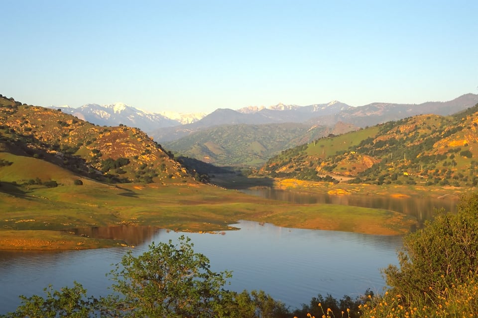 A valley with a lake surrounded by hills and mountains.