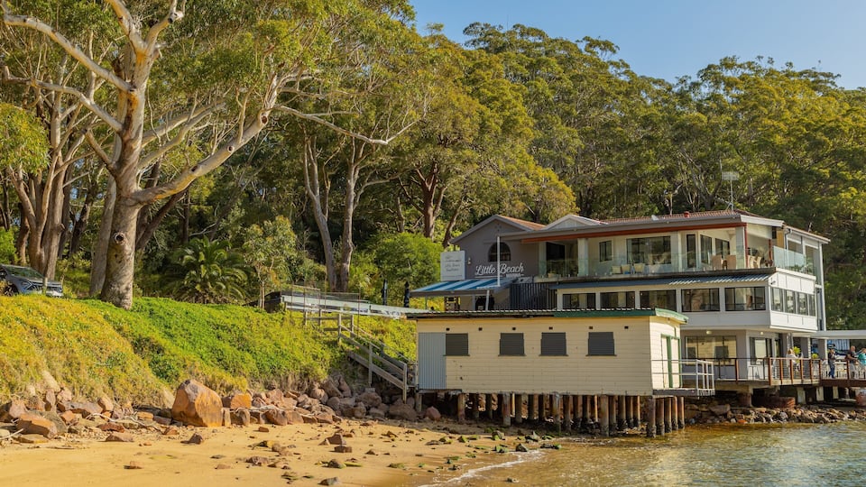 A waterfront property with a two-story house, a dock, and a beach.