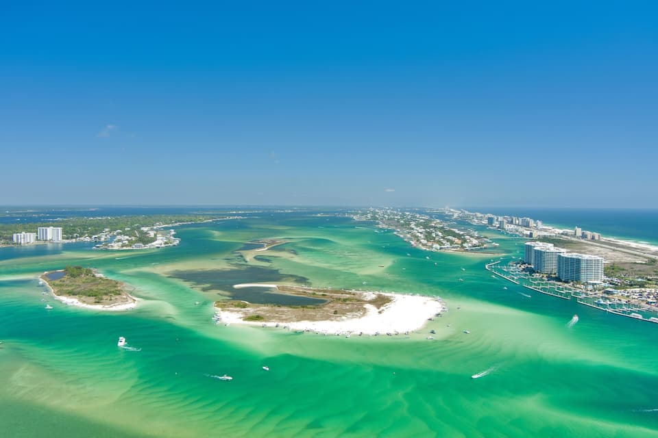 An aerial view of a coastal city with clear blue waters, a marina, and several islands.