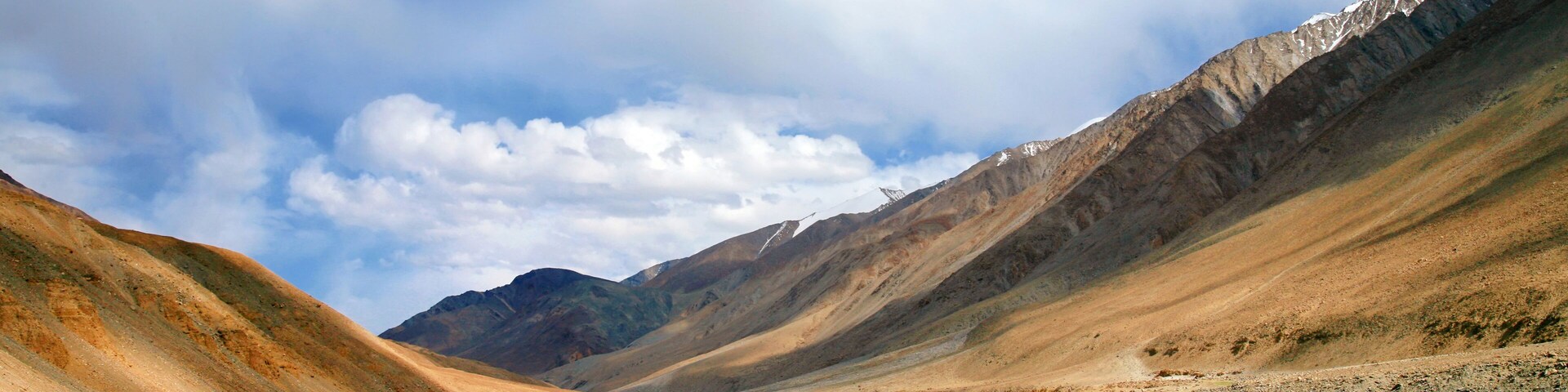 Un paisaje montañoso con un valle, un río y un pico nevado.