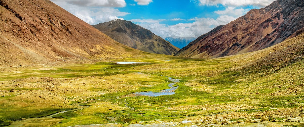 A valley with a river, mountains, and a clear sky.