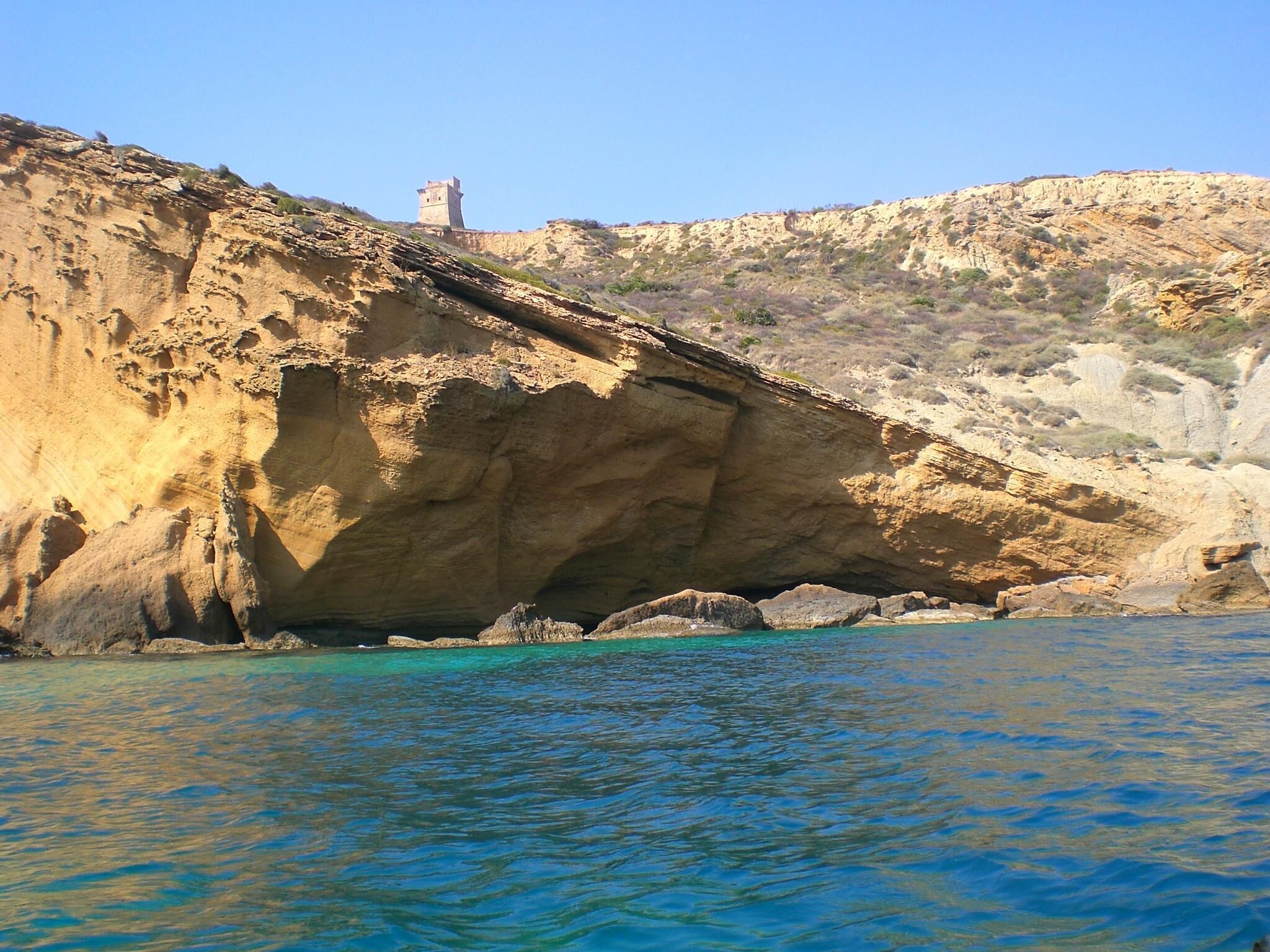 A coastal landscape with a rocky cliff and a tower on top.