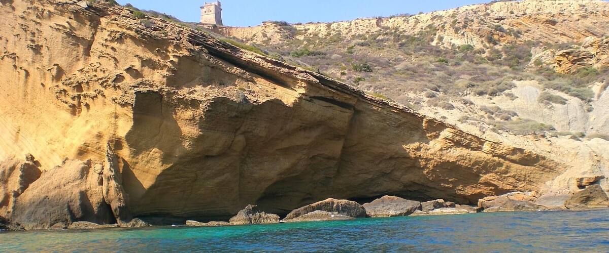 A coastal landscape with a rocky cliff and a tower on top.