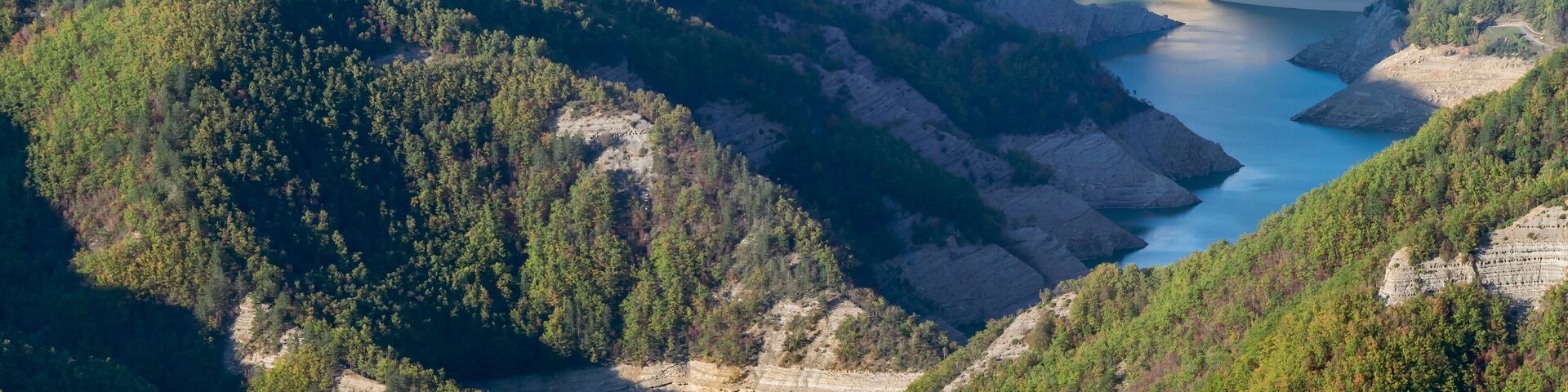 Una presa en una zona montañosa con un río que la atraviesa.