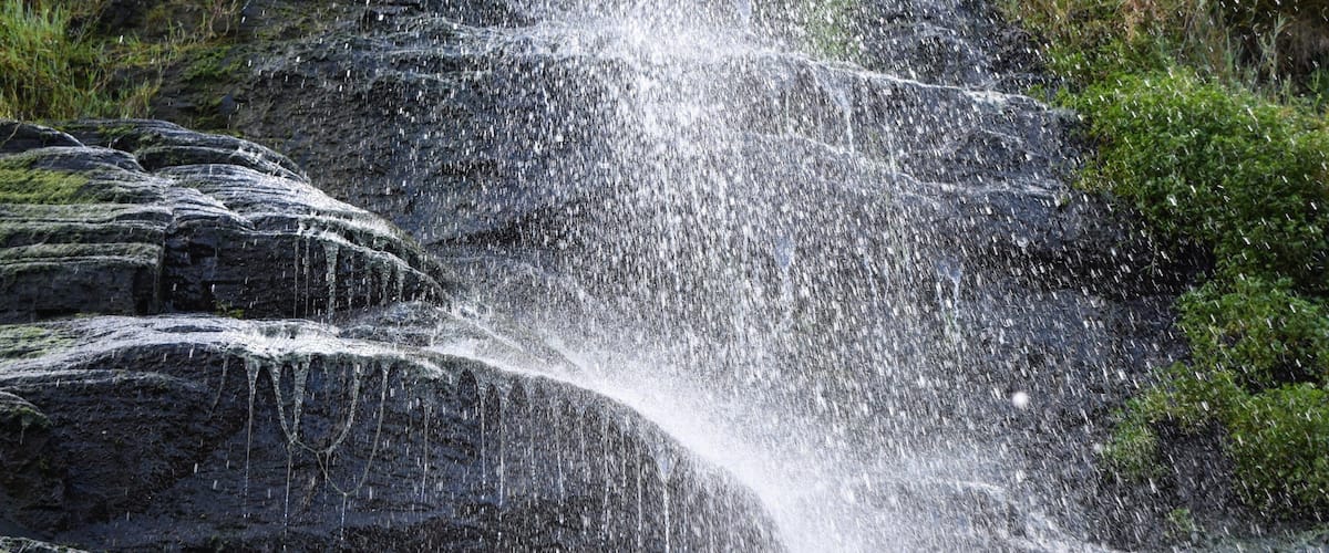 A waterfall cascading over rocky terrain with lush greenery around.