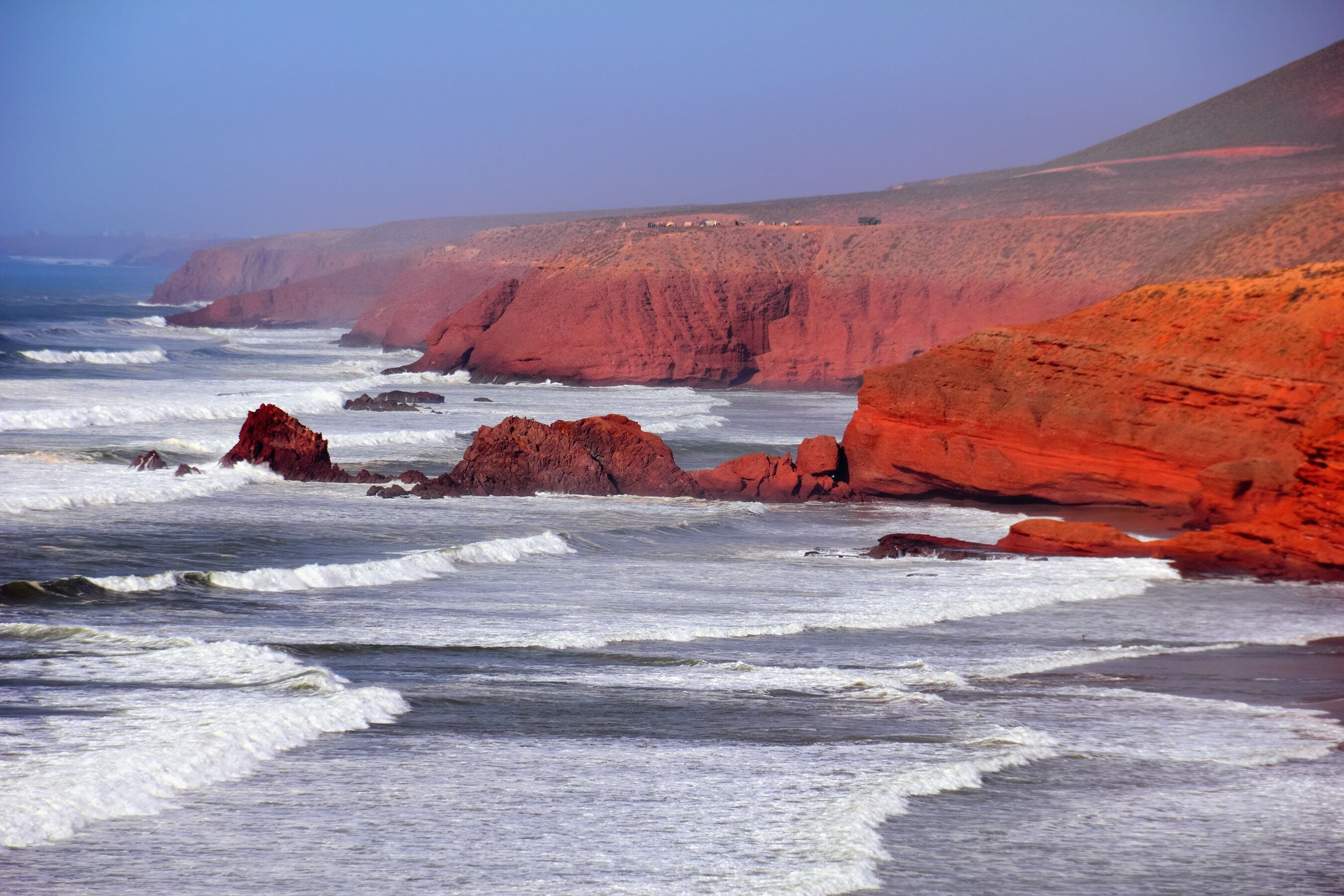 Rocky coast of Atlantic ocean, waves, sea surf, red rocks, ruins of famous mountain arch and blue evening sky. Beautiful nature view in Legzira beach, Sidi Ifni, Morocco, North West Africa.
