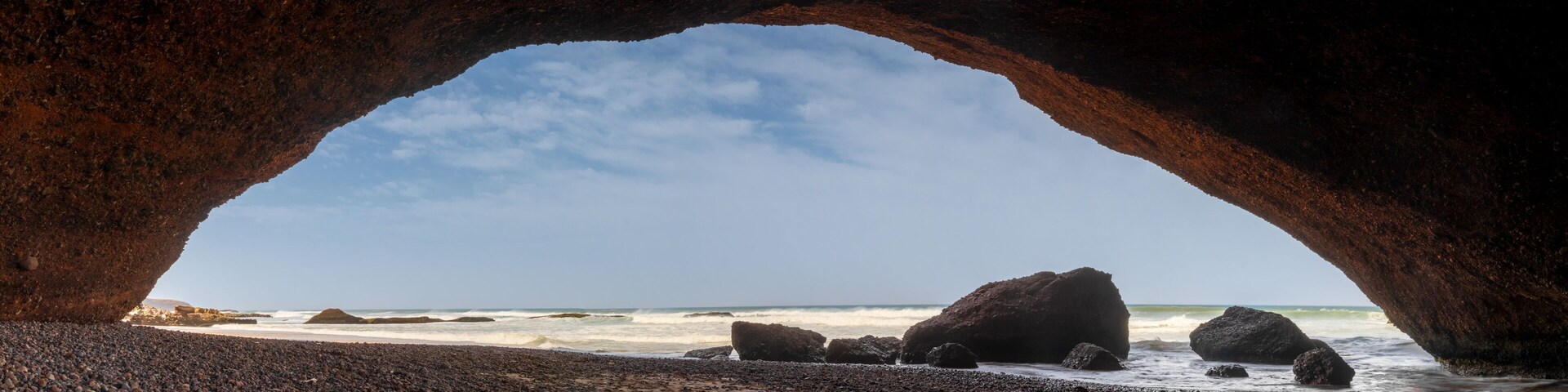 Una playa rocosa con un arco que da al océano.