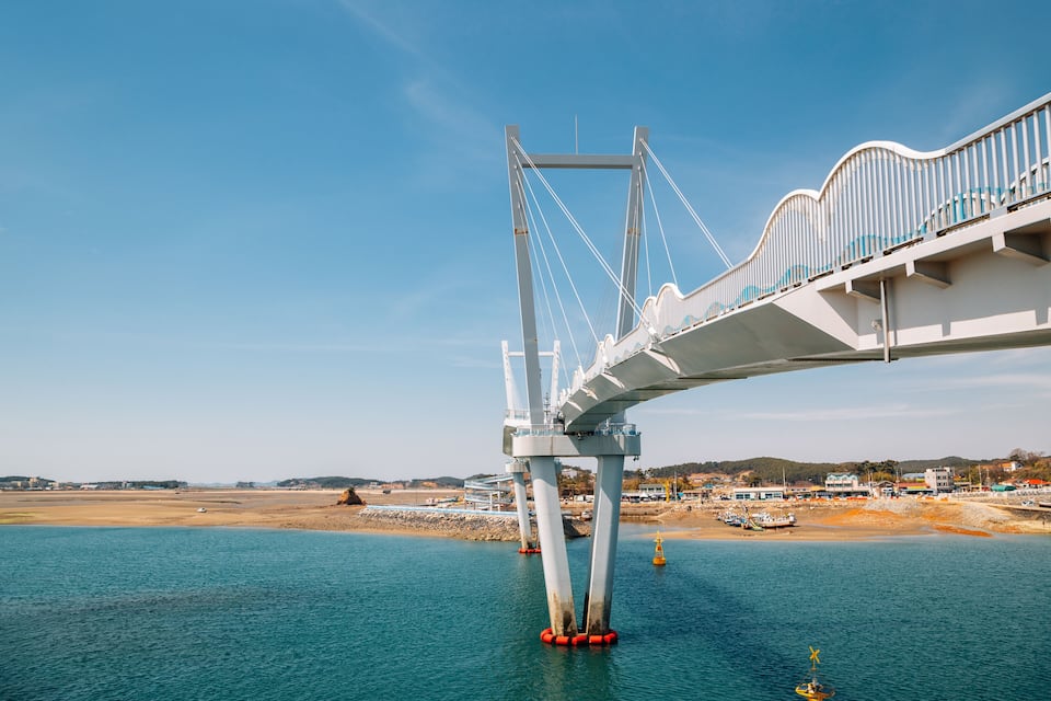 Un pont gran i blanc amb elements de suport vermells sobre una massa d'aigua.