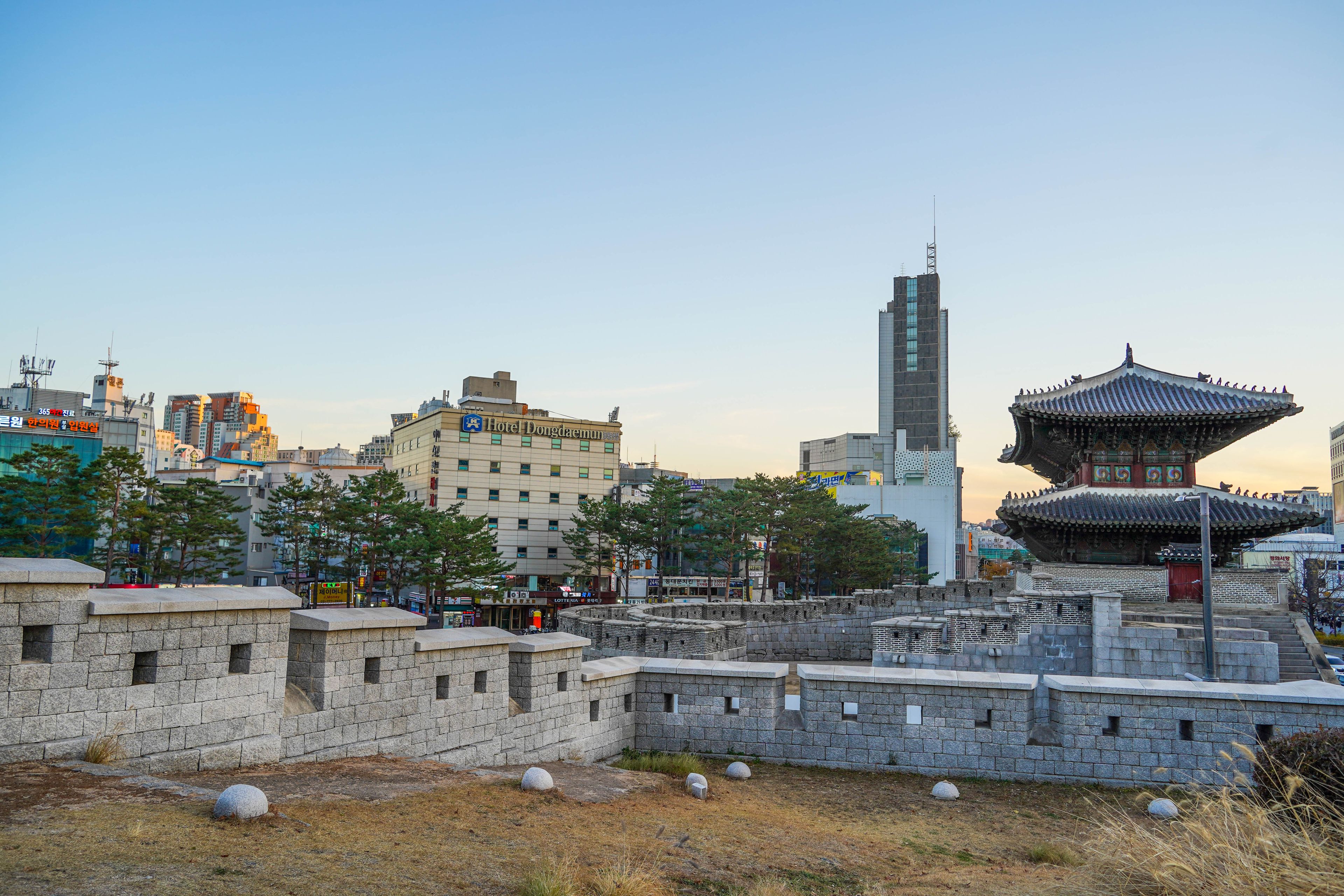 A traditional Korean gate, a modern building, and a pagoda in an urban setting.