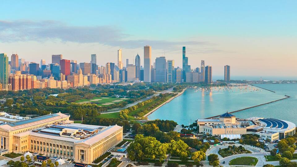 A city skyline with modern skyscrapers, a large museum, and a waterfront park.