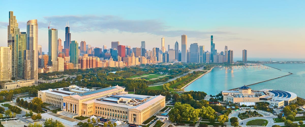 A city skyline with modern skyscrapers, a large museum, and a waterfront park.