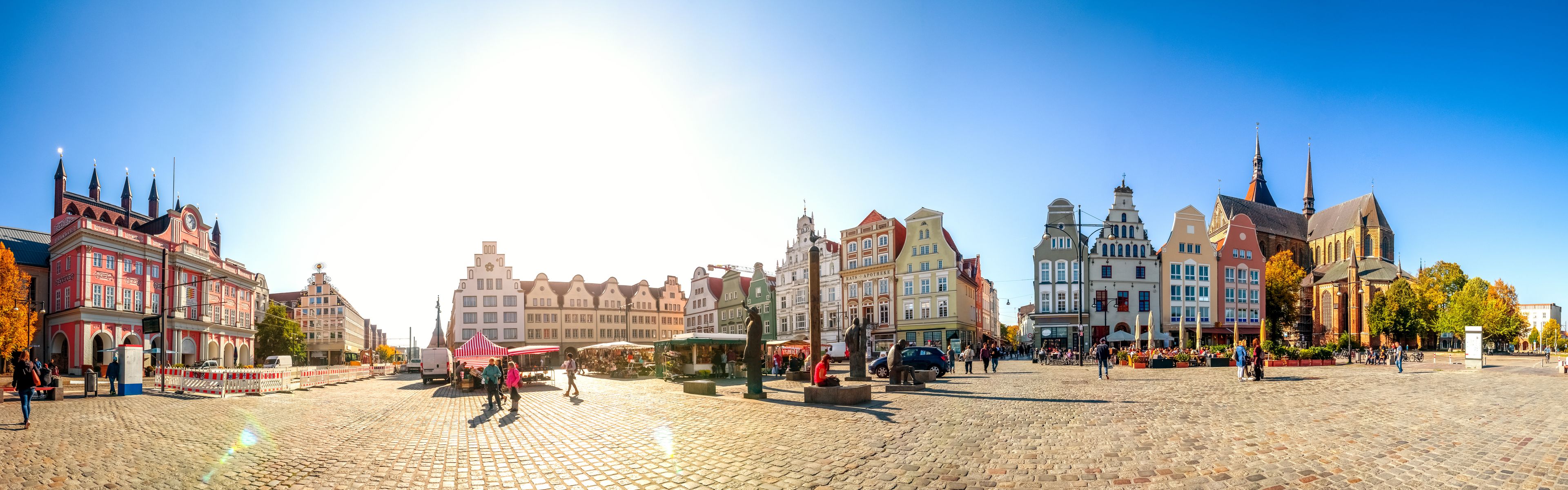 A cobblestone square with historic buildings, a statue, and a church.