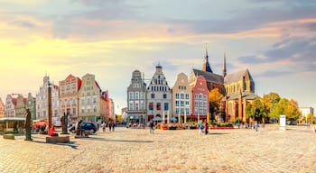 A cobblestone square with historic buildings, a church, and a market.