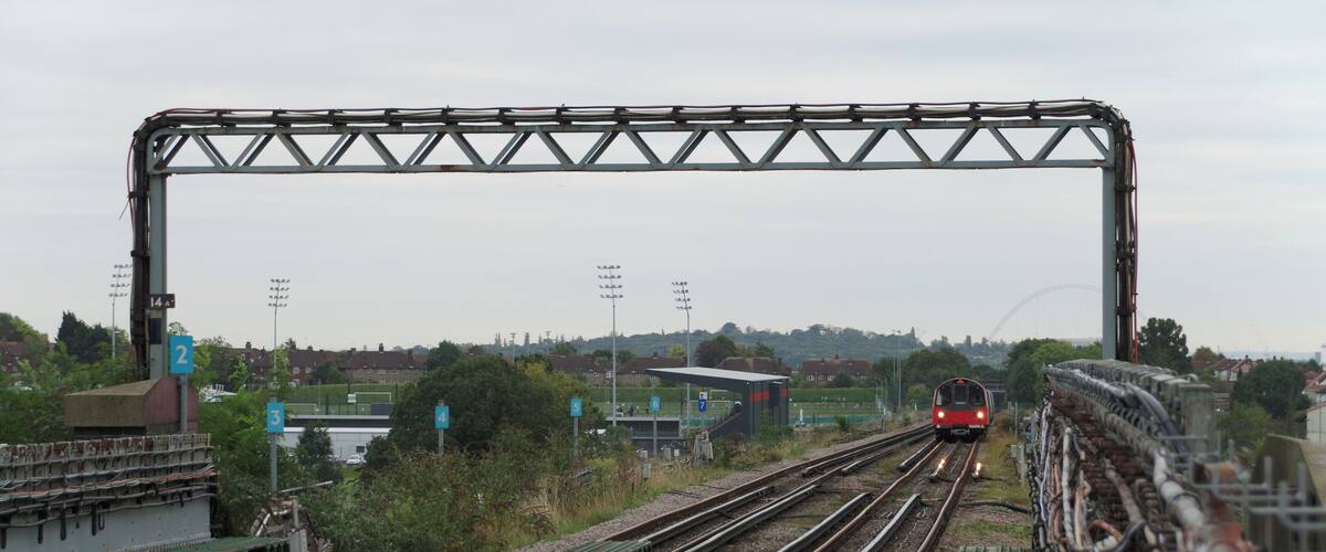 A train on tracks with a bridge overhead.