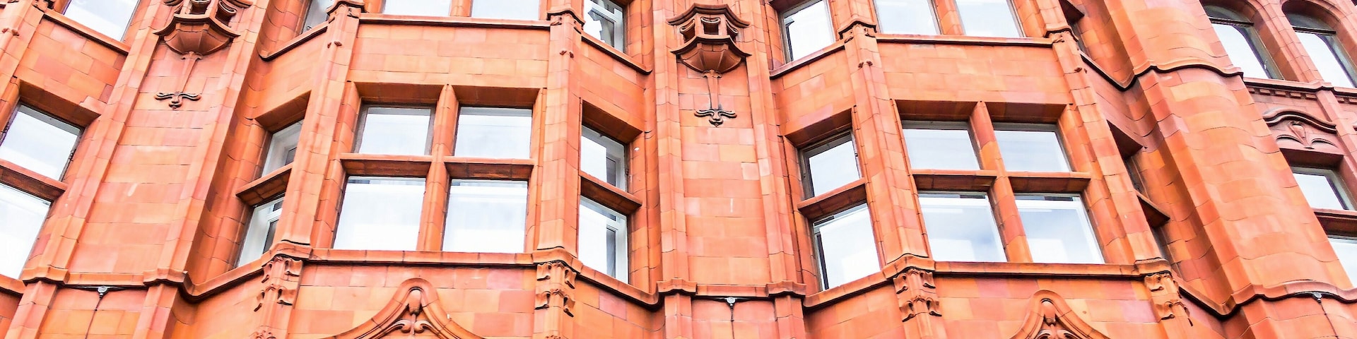 Un bâtiment en briques rouges, doté de détails architecturaux élaborés et de nombreuses fenêtres.