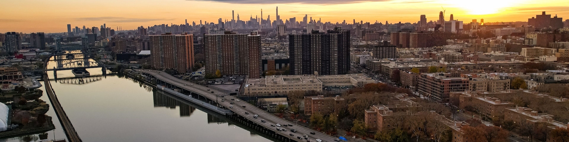 A city skyline at sunset with a river and bridges.
