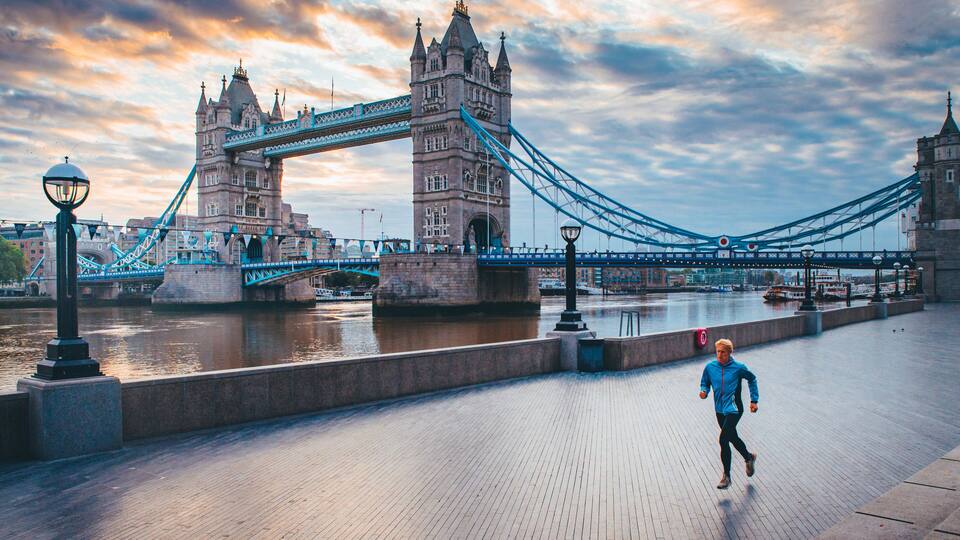 Alone runner in empty streets of london in Coronavirus, Covid-19 quarantine time. Tower Bridge in background