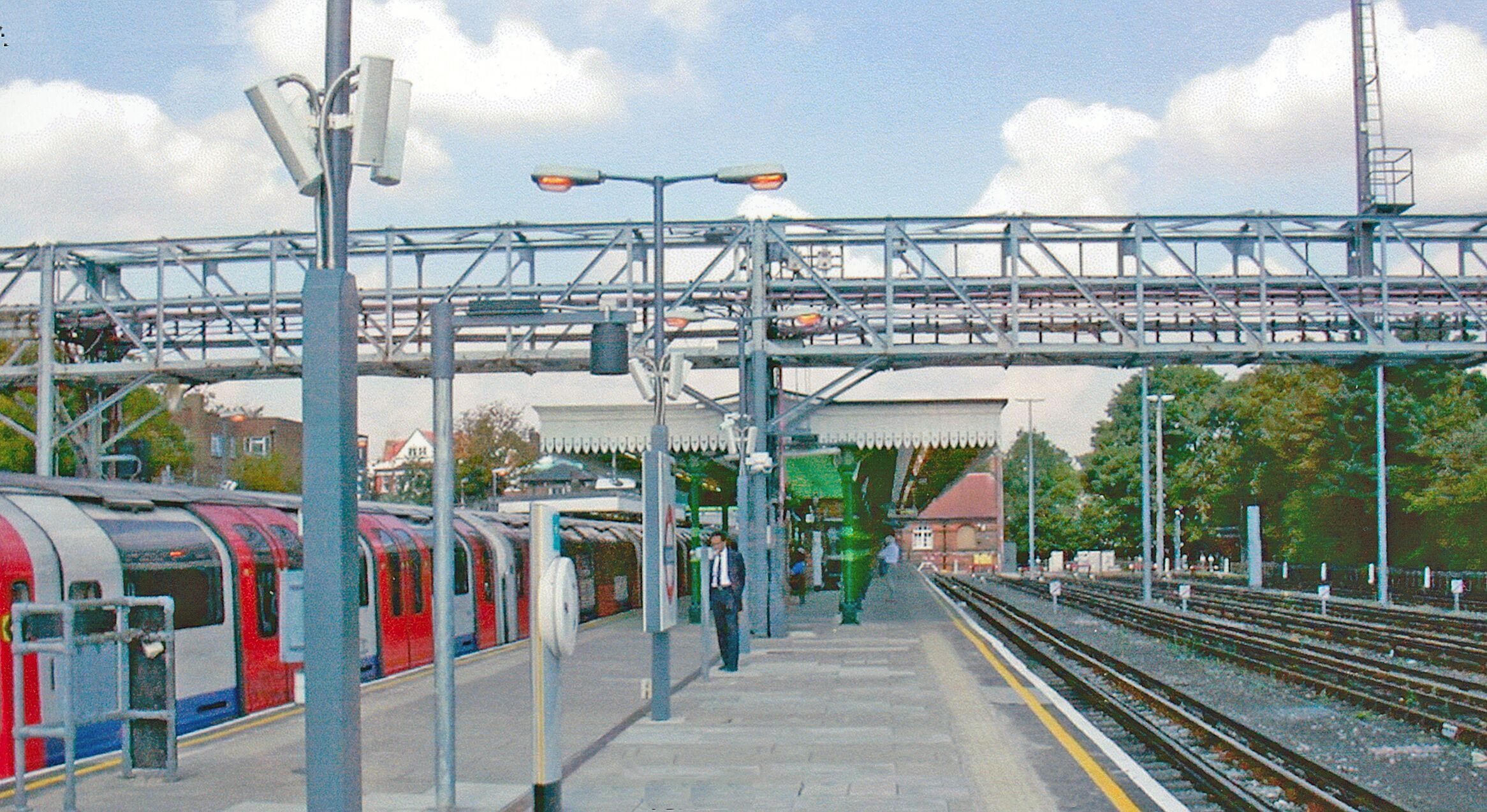 Woodford Station. View northward, towards Loughton and Epping, also Hainault: formerly the ex-GER Liverpool Street - Leyton - Loughton - Epping line, junction of Fairlop Loop via Hainault to Ilford. Passenger services were taken over by the LPTB Central Line in 1946-49, those on the Fairlop Loop south of Hainault using a new Tube tunnel between Leytonstone and Newbury Park; freight traffic ceased after 4/66. The Central Line Underground train on the left was probably from Ealing Broadway to Hainault.