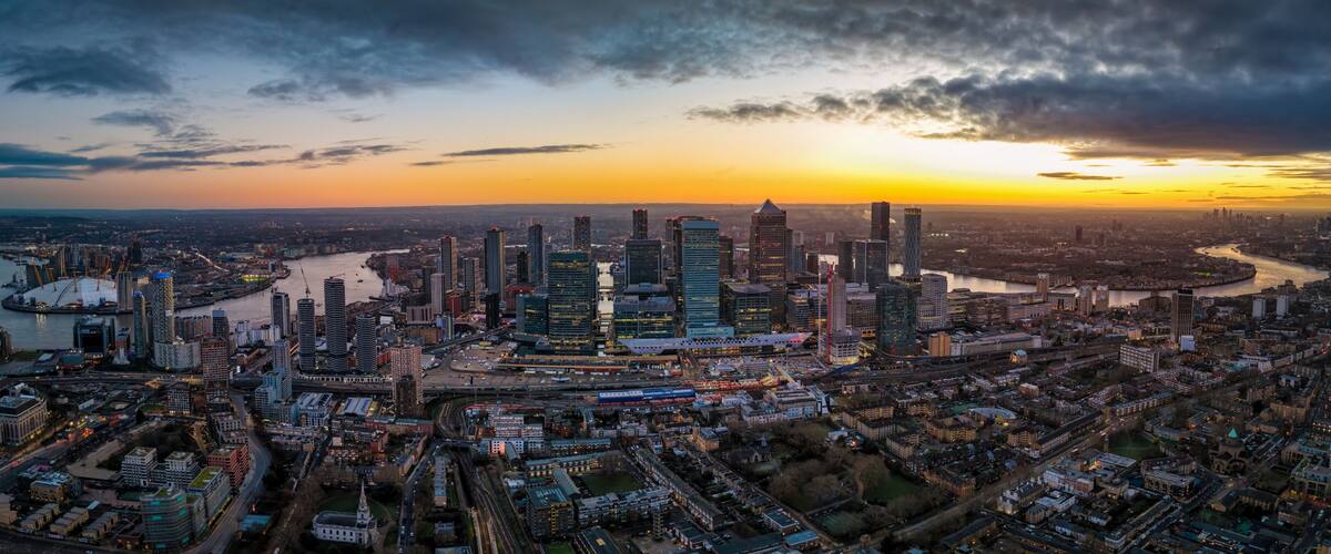Panoramic aerial view of the iilluminated skyline of London, England, stretching from Greenwich over Canary Wharf along river Thames until Tower Bridge and the City during dusk