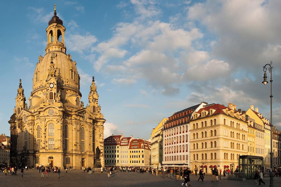 Una catedral histórica con una cúpula destacada y un campanario, rodeada de edificios tradicionales europeos.
