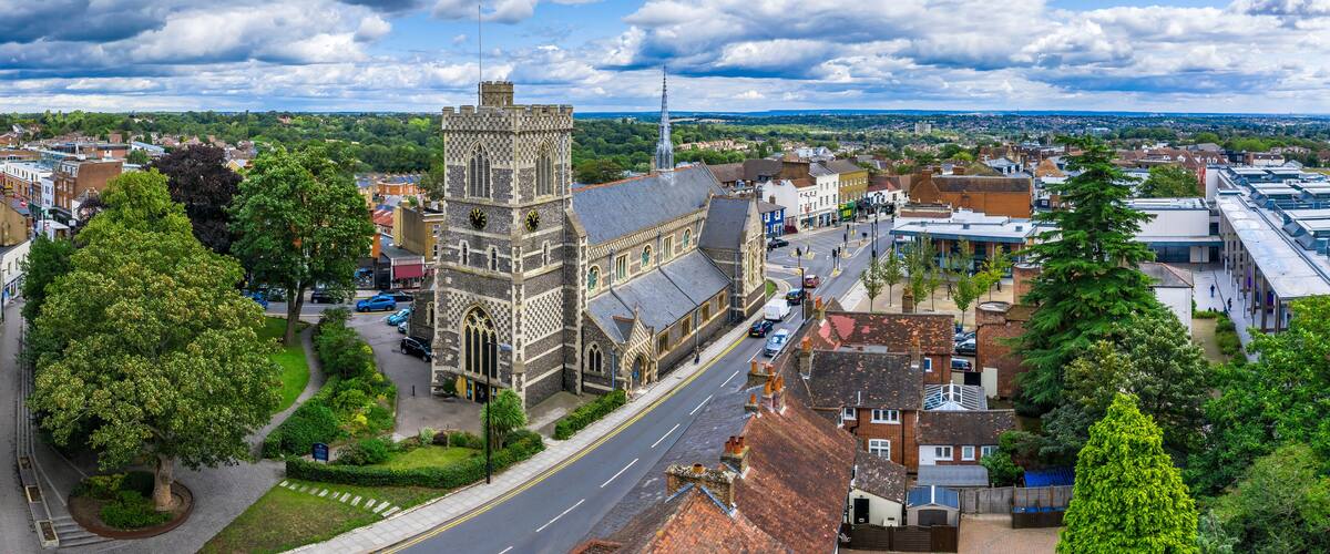 A historic church with a tall tower, surrounded by residential buildings and a clear sky.