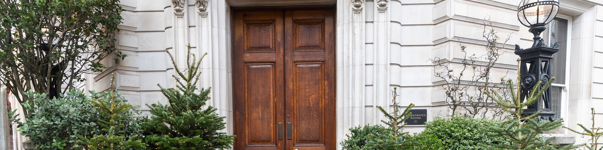 London, UK - December 02, 2024: Bow Street Magistrates' Court. Entrance to the historic building with a wooden door, decorated with Christmas trees around it...