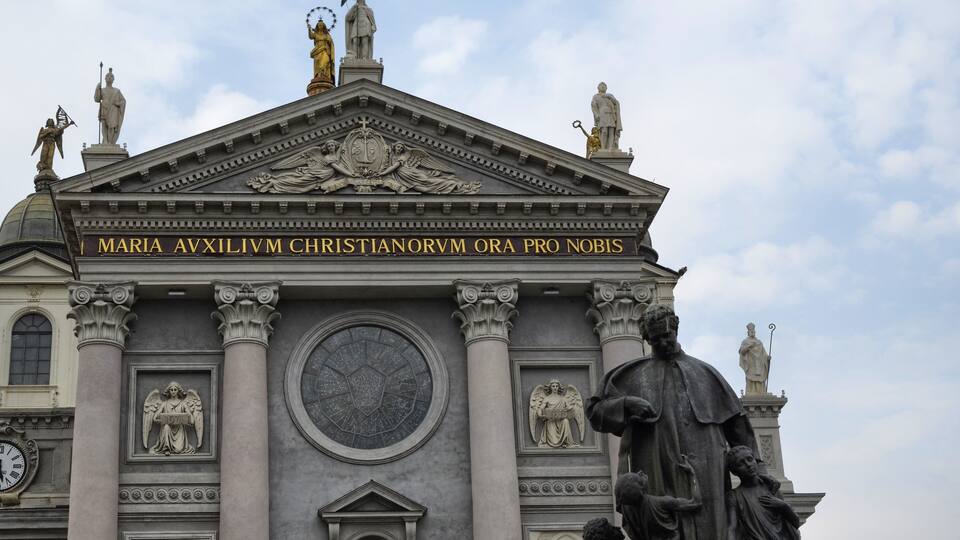 Ein prachtvolles Gebäude im klassischen Stil, mit Statuen und einer Inschrift.
