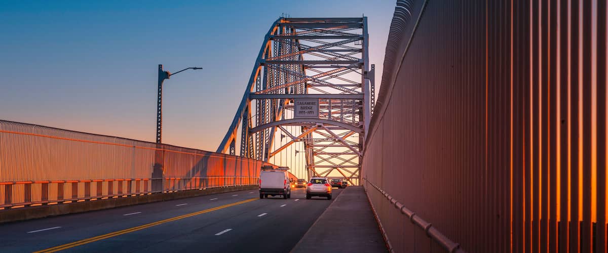 Sagamore Bridge at Sunrise over Cape Cod Canal. Glowing Gold Silhouette Architectural Image. High Contrast Panoramic Backdrop with Space for Text and Design.