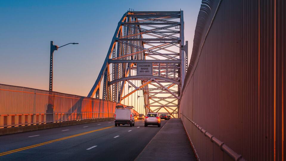 Sagamore Bridge at Sunrise over Cape Cod Canal. Glowing Gold Silhouette Architectural Image. High Contrast Panoramic Backdrop with Space for Text and Design.