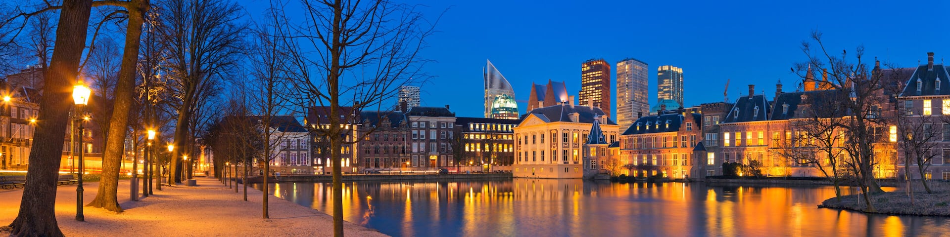 A river reflecting city lights, with historic buildings and modern skyscrapers along the banks.