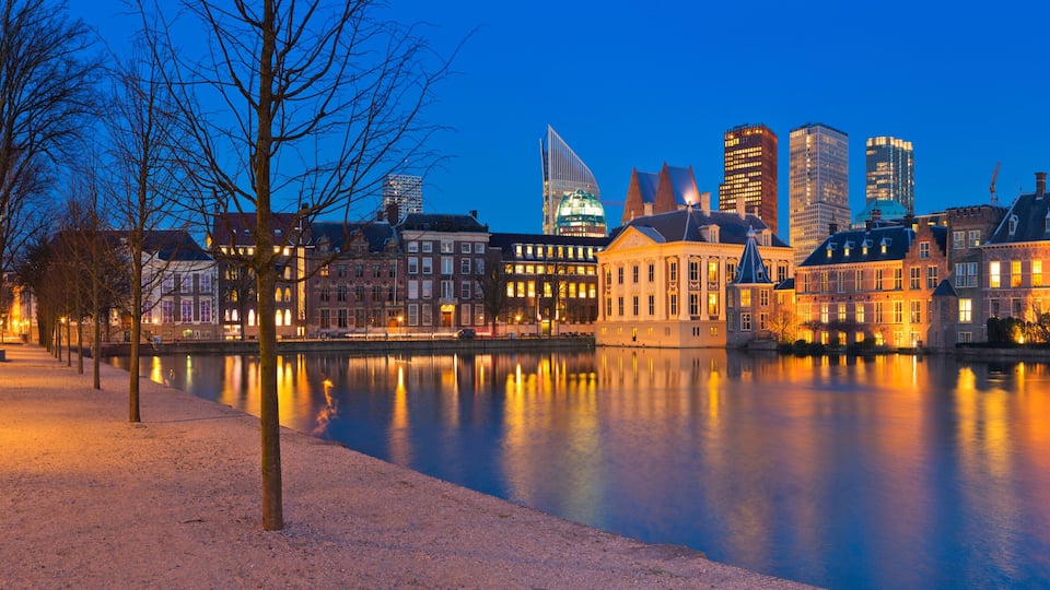 A river reflecting city lights, with historic buildings and modern skyscrapers along the banks.