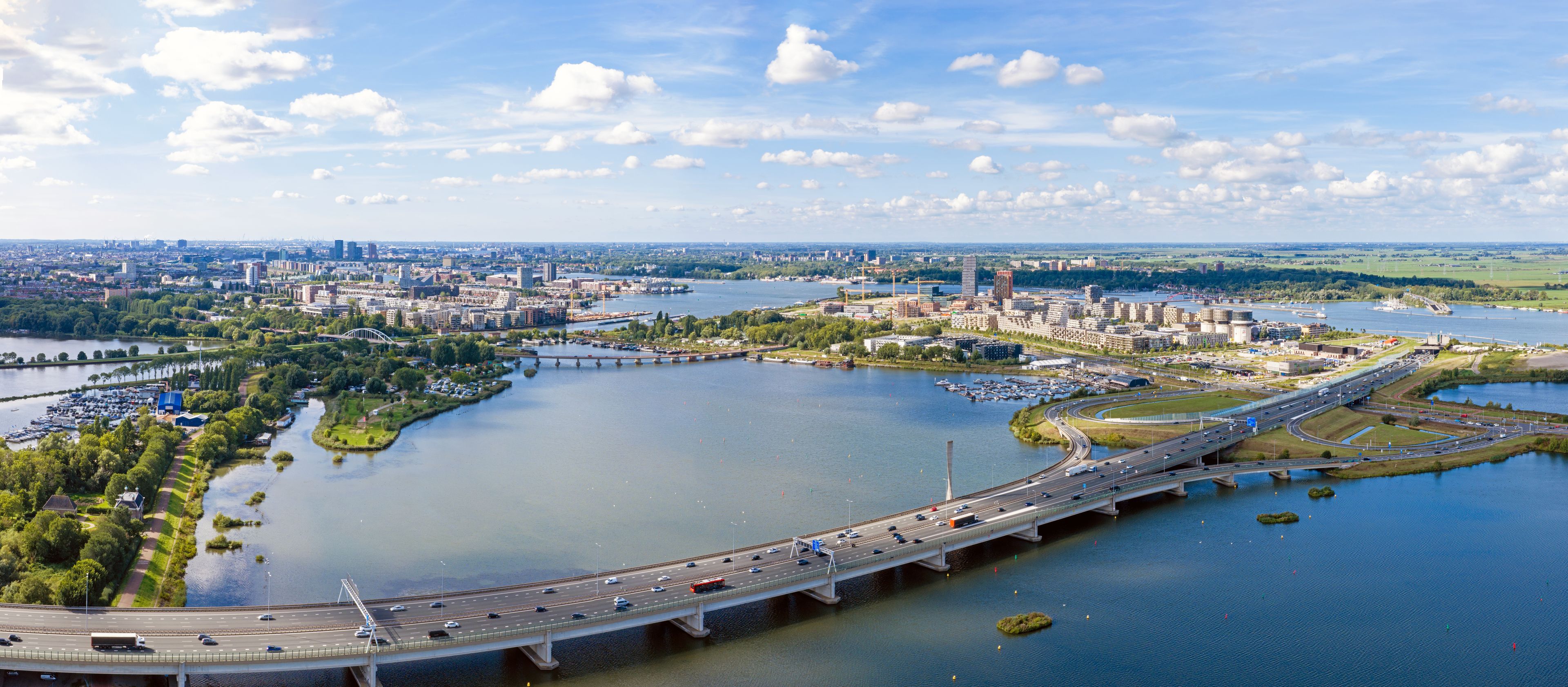 Un río con un puente, un paisaje urbano con edificios y una vista distante del horizonte de la ciudad.