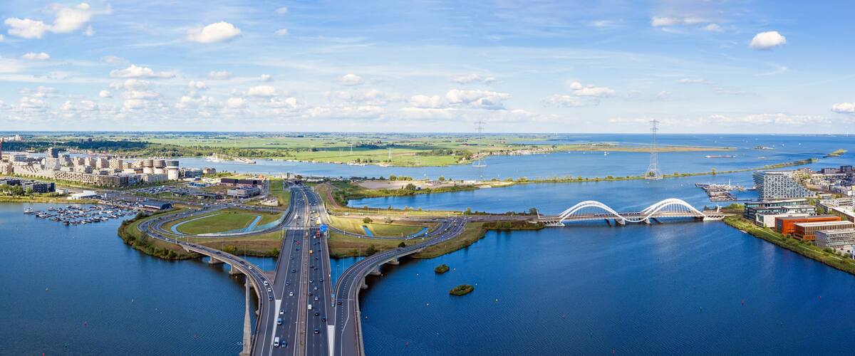 Aerial view of Amsterdam, the Netherlands, featuring the A10 motorway, Zeeburgereiland, the Enneus Heerma Bridge and urban infrastructure.
