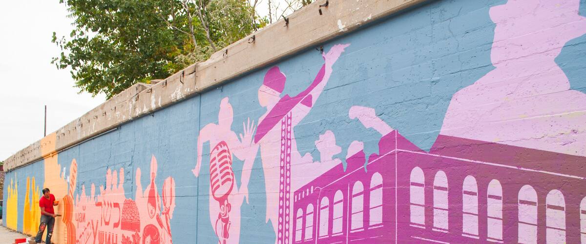 artist paints mural on a city street