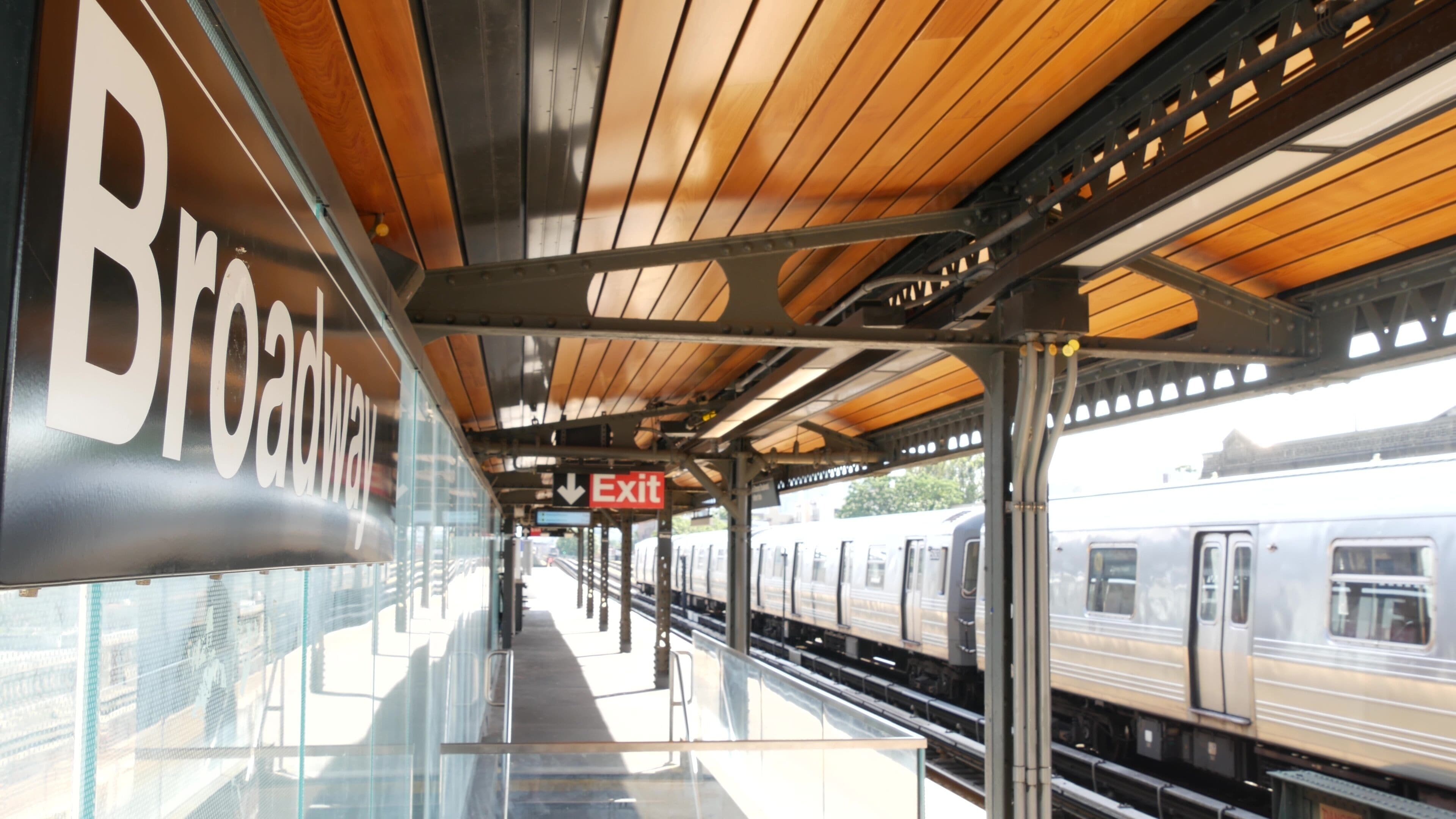 New York subway station Broadway text sign. Metropolitan train on platform, United States public metro transportation. Elevated outdoor railway line, Astoria, Queens. NYC passenger railroad traffic.