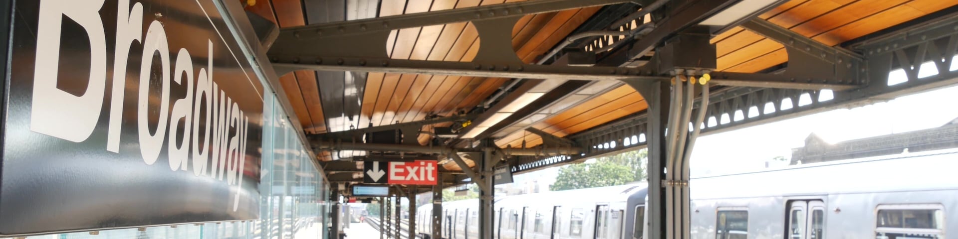 New York subway station Broadway text sign. Metropolitan train on platform, United States public metro transportation. Elevated outdoor railway line, Astoria, Queens. NYC passenger railroad traffic.