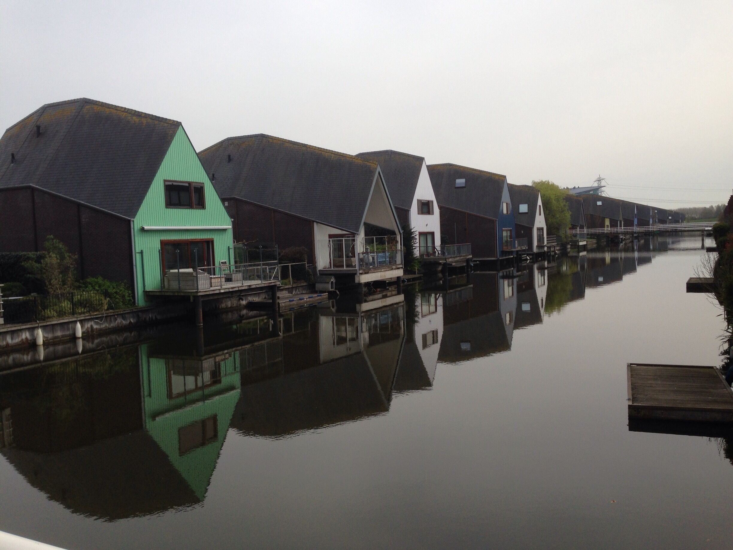 A canal with houses reflecting on the water.