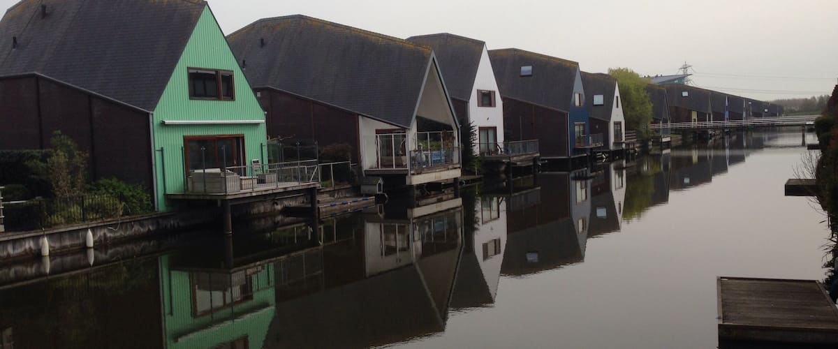 A canal with houses reflecting on the water.