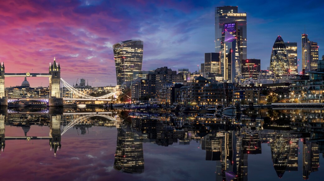 The lit urban skyline with City of London and Tower Bridge just after sunset time with reflections in the river Thames, United Kingdom