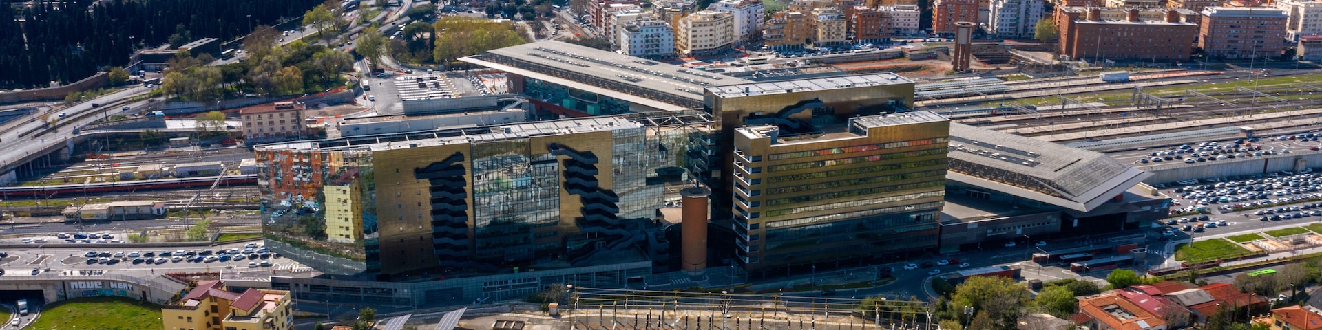 Un paysage urbain caractĂ©risĂ© par une architecture moderne, notamment un bĂątiment remarquable dotĂ© dâune grande structure en forme dâaile, entourĂ© dâun tissu urbain dense et traversĂ© par une autoroute.