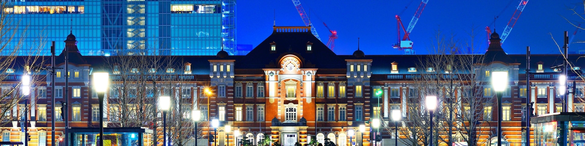 Un bâtiment historique à l’architecture riche et ornée, avec un arrêt de tramway et des grues de construction en arrière-plan.