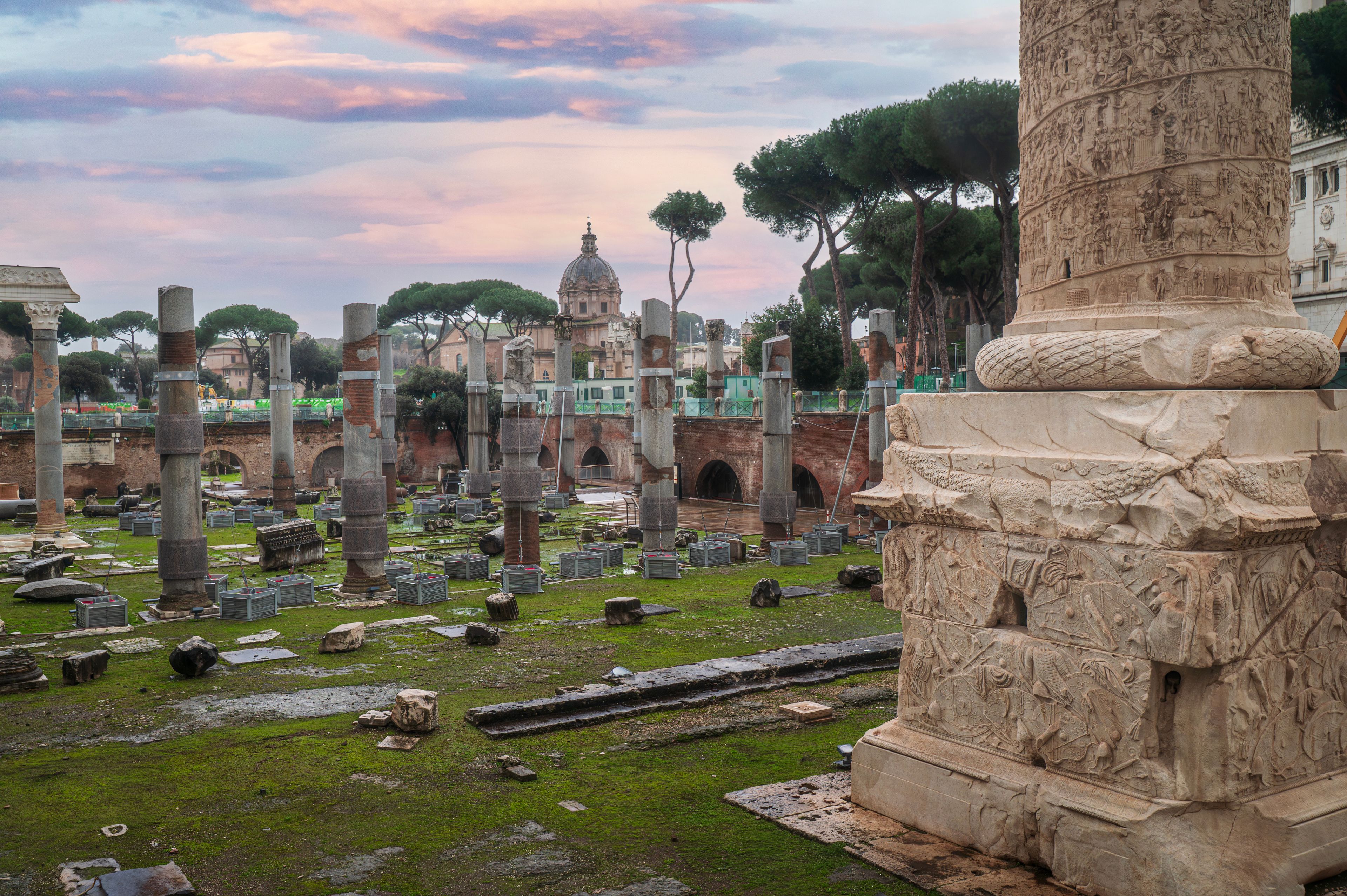 Ancient ruins with columns and a domed building in the background.