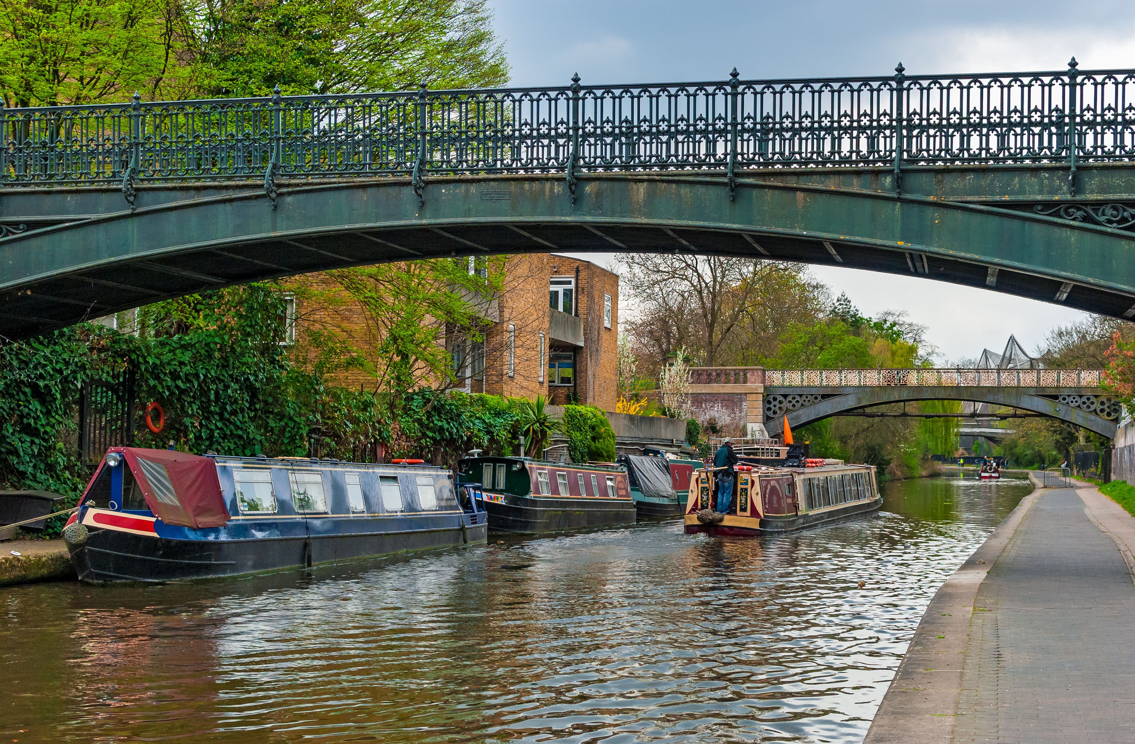 Un canal con barcos, un puente y edificios al fondo.