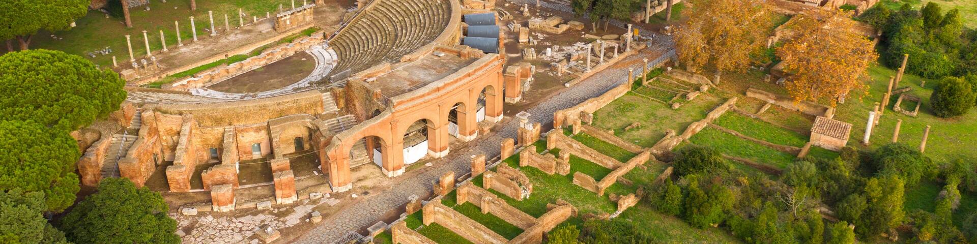 An ancient amphitheater surrounded by trees and ruins.