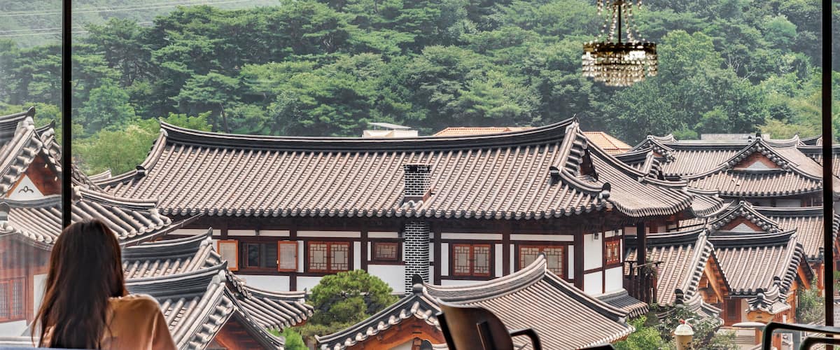 대한민국 서울 은평구 은평한옥마을에 있는 카페에 앉아 있는 여자와 창문 밖으로 한옥마을이 보이는 풍경