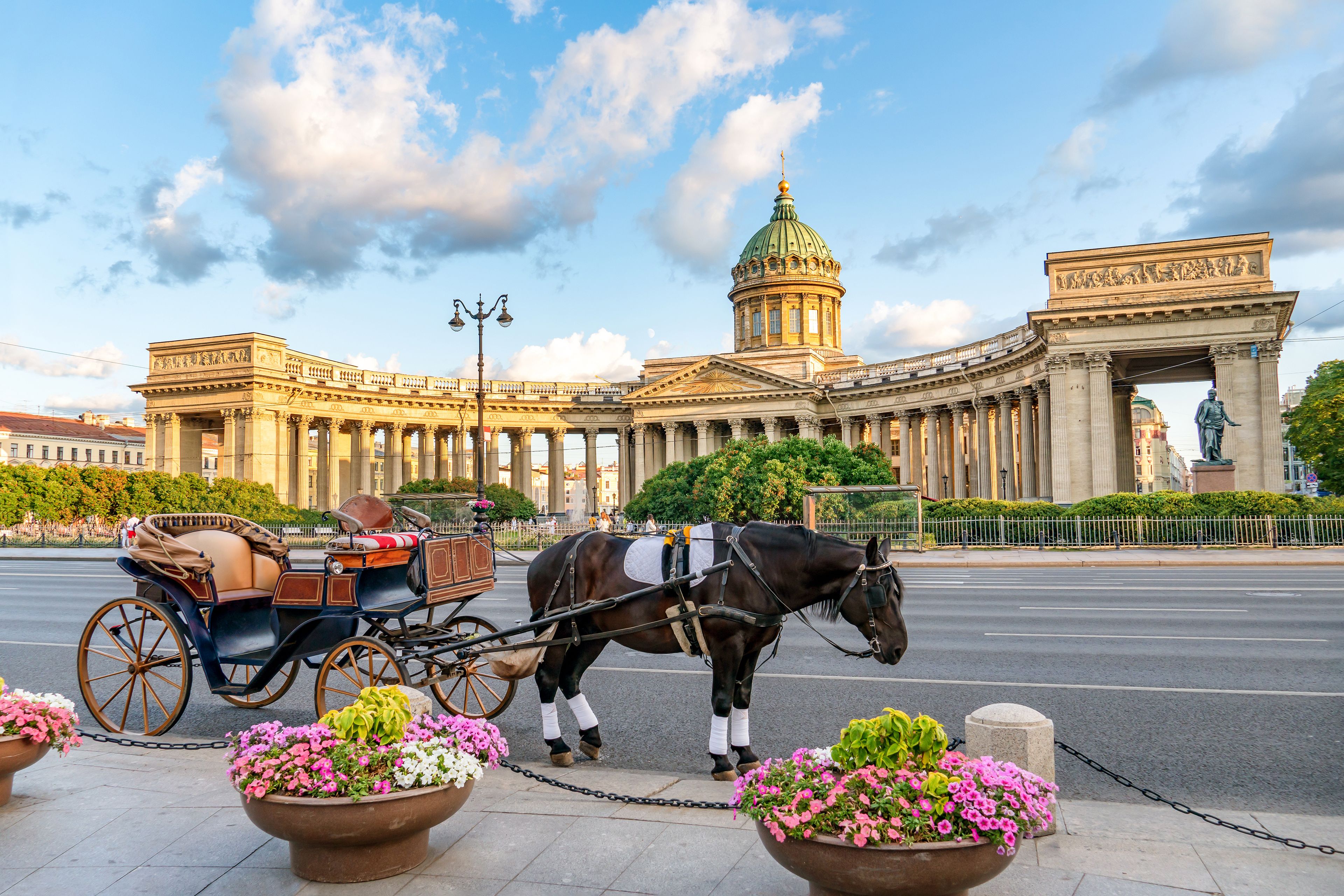 A horse-drawn carriage in front of a grand building with a dome and an archway.
