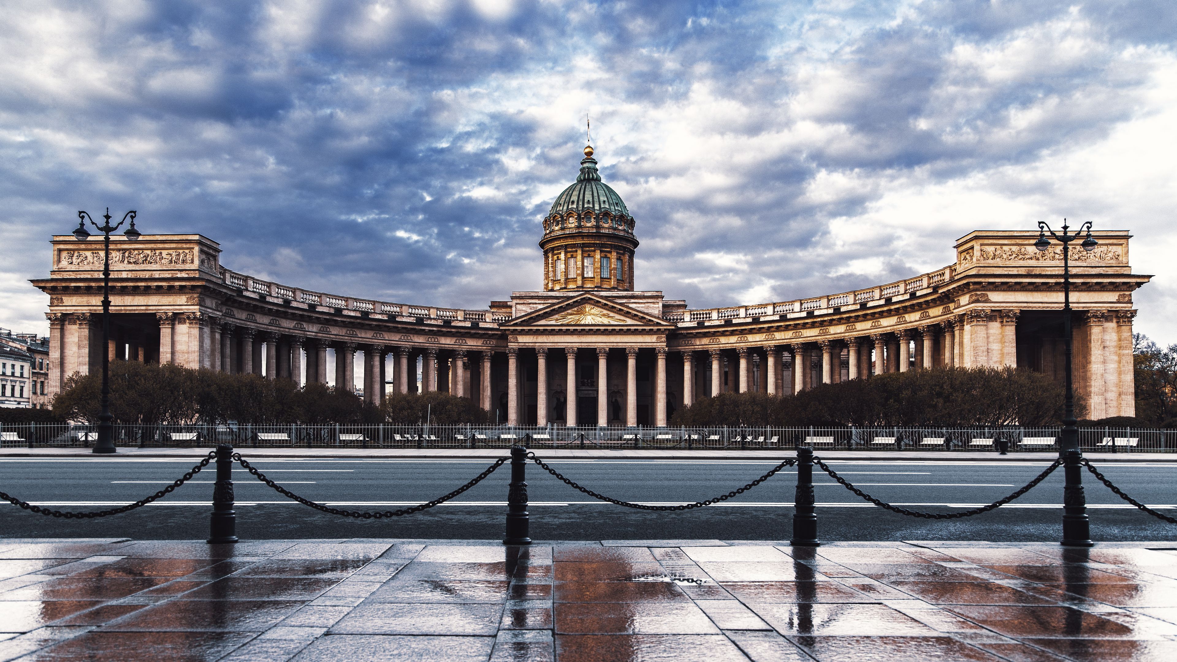A grand neoclassical building with a central dome and flanking wings, surrounded by a chain-link fence.