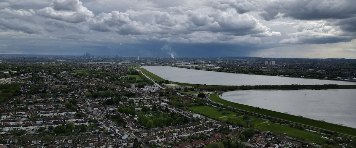 A river curving through a city with dense residential areas and a cloudy sky.