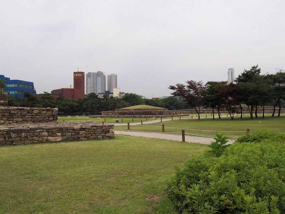 Several tombs located just south of Jamsil. These belong to the Baekje Kingdom, which ruled approximately the western half of modern-day South Korea from 18 BC to 660. Baekje's first capital was located in this general area, and there is another tomb complex about a mile to the northeast. These tombs used to be in a state of decay, with the complex bisected by a modern boulevard, as archaeology was an unaffordable luxury until the 1970s. But in the 1980s, excavation and restoration took place, and the boulevard was put through an underground tunnel. Further away I can see the modern developments that mark today's Seoul: a Protestant church, three high-rise condominium buildings, and Hotel Lotte World. Jamsil area would gain dozens more high-rise condominiums over the next few years.