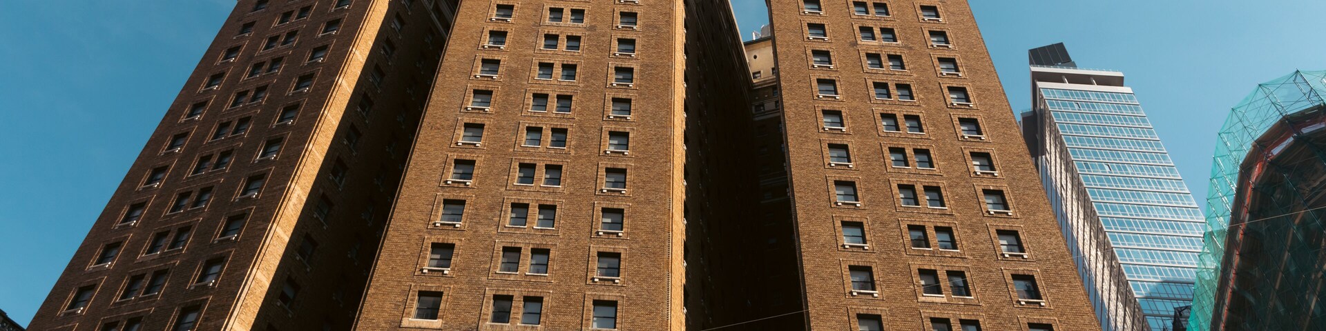 A tall, brown brick building with a clear blue sky in the background.